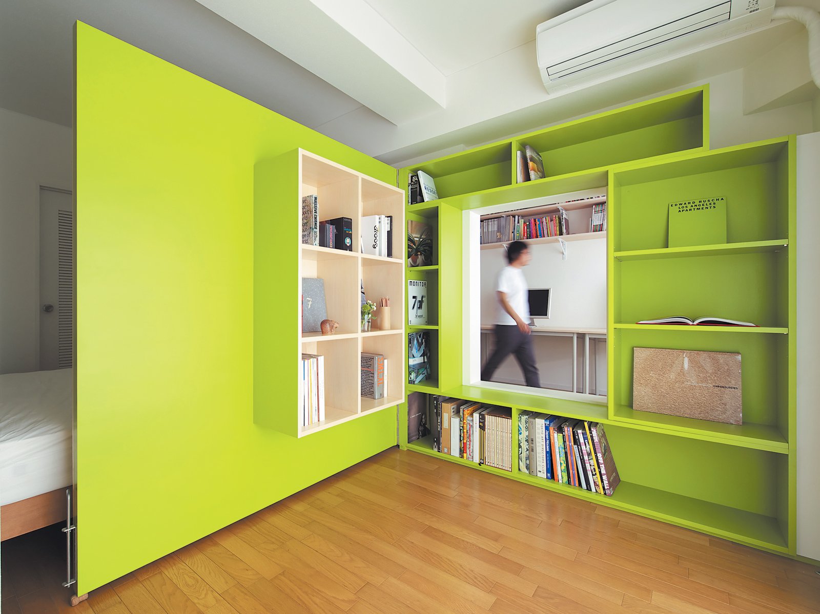 customized bookshelves berwarna lime green sebagai area penyimpanan di apartemen / ryohei hamada / dwell